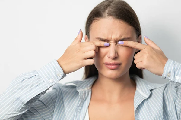 Mujer tocando los ojos de pie sobre fondo blanco, Estudio — Foto de Stock