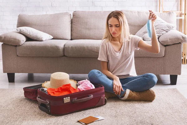Жінка сумно виглядає на валізі з одягом — стокове фото