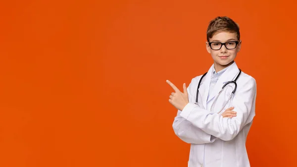 Allvarlig tonåring i läkaruniform pekar på tomt utrymme — Stockfoto
