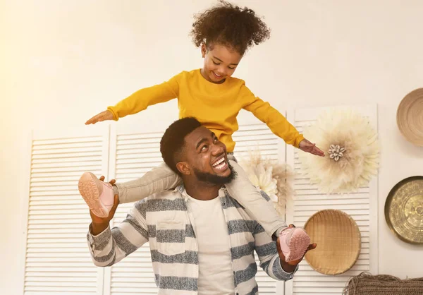 Afrikalı Amerikalı baba kızı omuzlarında tutarken eğleniyor. — Stok fotoğraf