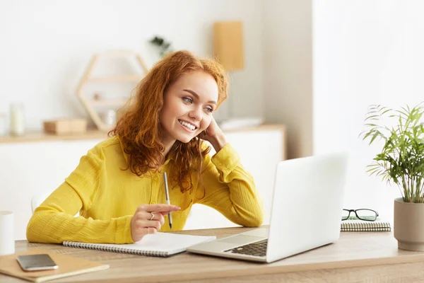 Ung kvinne som jobber med laptop og skriver notater – stockfoto