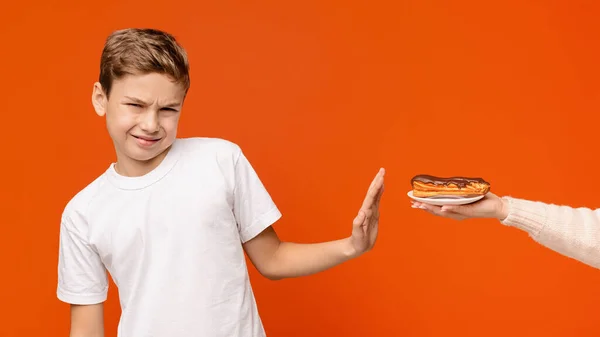 Dospívající chlapec cítí znechucení, odmítá čokoládové koblihy — Stock fotografie