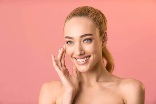 Sorridente signora applicazione di crema viso guardando oltre in posa in studio — Foto Stock