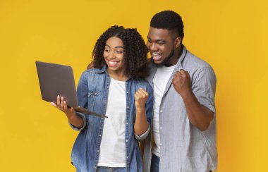 Gülümseyen Afrikalı Amerikalı çift laptopta spor izliyor ve tezahürat yapıyor.