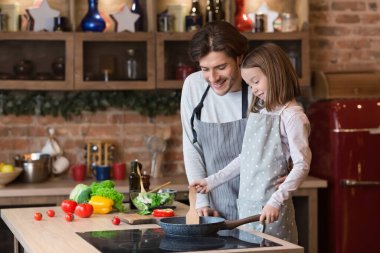 Babası tatlı kızına tavada nasıl yemek pişirileceğini öğretiyor.