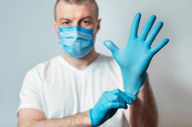 Tıbbi Maskeli Adam Gri Arkaplan Üzerine Eldiven Giyiyor