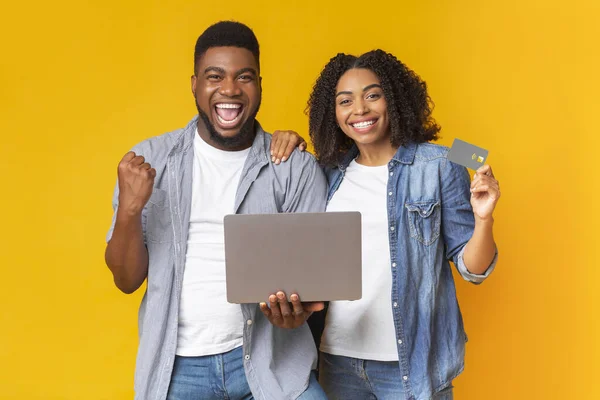 Gioiosa coppia africana che celebra il successo con laptop e carta di credito — Foto Stock