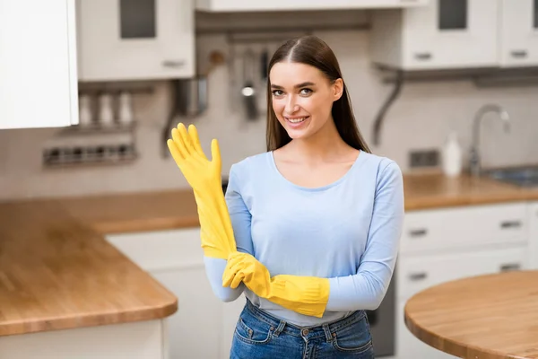 Jonge vrouw trekt gele rubberen handschoenen aan — Stockfoto