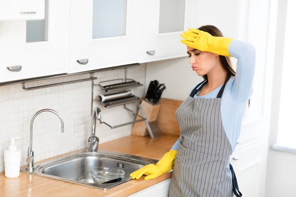 Tired woman wearing yellow rubber gloves washing dishes — Stock Photo, Image
