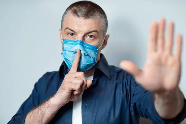 Mężczyzna w masce medycznej Gesturing Hush znak na szarym tle — Zdjęcie stockowe