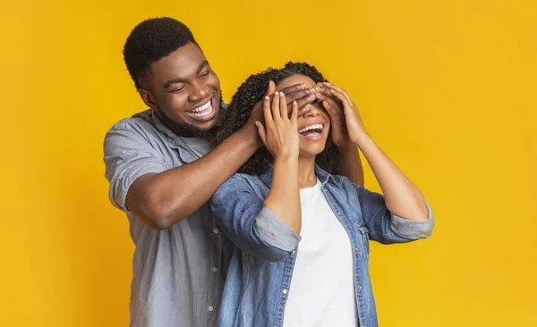 Adivina quién. Afectuoso hombre negro sorprendiendo a su esposa, cubriendo sus ojos — Foto de Stock