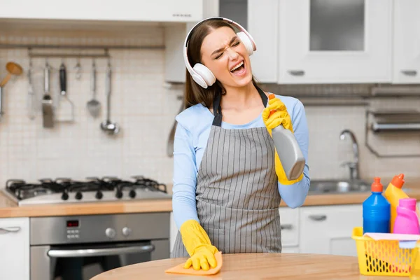 Glad ung kvinna med hörlurar rengöringsbord — Stockfoto