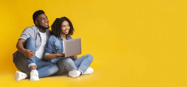 Couple noir souriant assis avec ordinateur portable et regardant l'espace de copie — Photo