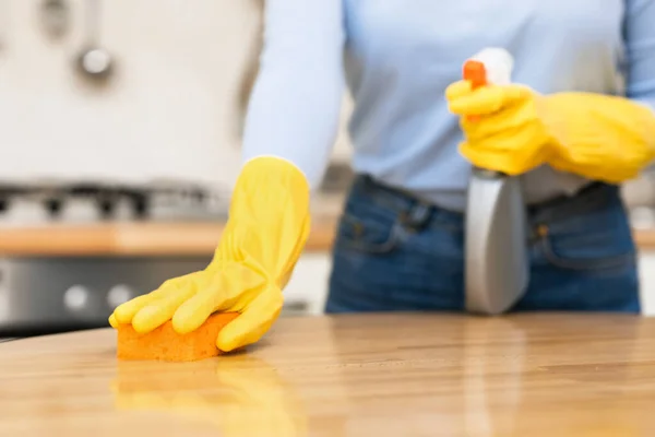 Młoda kobieta sprzątanie stołu kuchennego za pomocą sprayu i gąbki — Zdjęcie stockowe