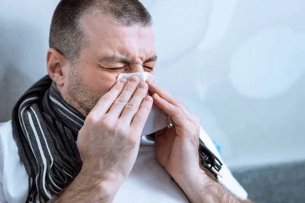 Man blazen neus in weefsel hebben koorts liggend in bed — Stockfoto