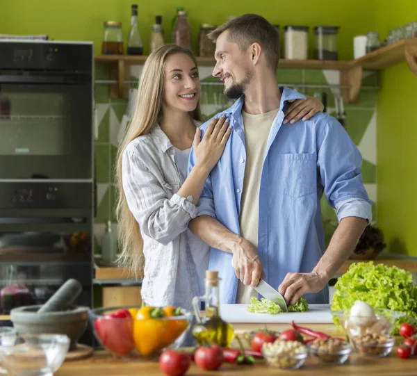 Man och kvinna i sitt kök hemma tillagar middag — Stockfoto