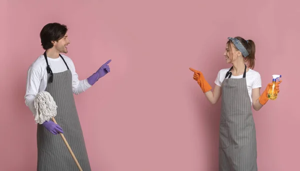 Boldog pár tisztítószerekkel a kezükben, akik a másolótérre mutogatnak — Stock Fotó