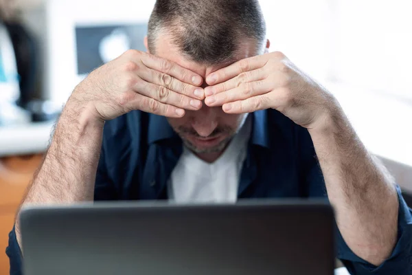 Hombre irreconocible en el ordenador portátil sentado teniendo problemas de negocio en casa —  Fotos de Stock