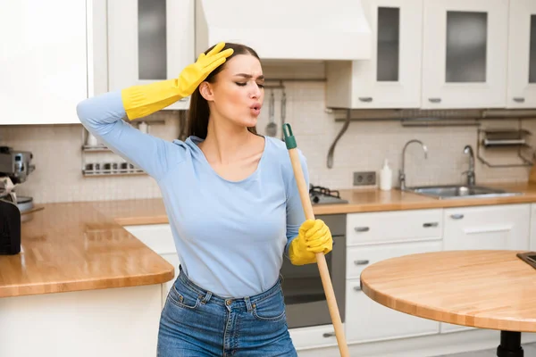 Happy young woman cleaning kitchen floor singing at mop — Stock Photo, Image