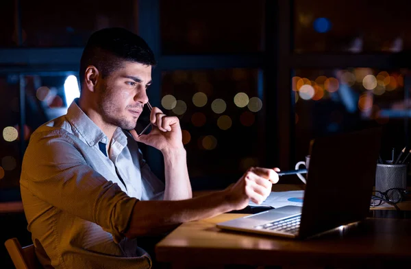 Επιχειρηματίας μιλάει στο τηλέφωνο κάθεται στο γραφείο τη νύχτα — Φωτογραφία Αρχείου
