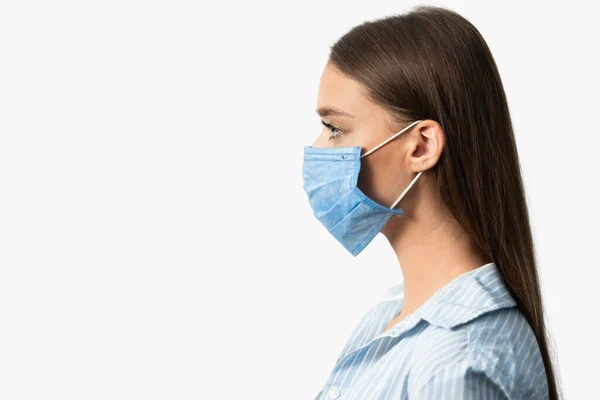 Meisje in medische masker poseren op witte studio achtergrond, zijaanzicht — Stockfoto