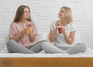 İki kız arkadaş konuşuyor ve sağlıklı detoks kokteylleri içiyor.