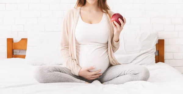 Wanita hamil makan apel merah organik, duduk di tempat tidur — Stok Foto