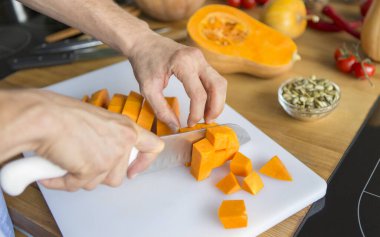 Vejetaryen kremalı çorba yapmak için balkabağı kesen adam.