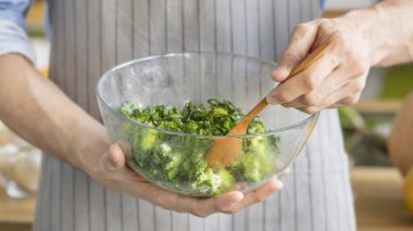 Adam lezzetli süper yemek salata malzemelerini ahşap kaşıkla karıştırıyor.