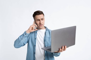 Telefonda konuşan ve dizüstü bilgisayarı olan bir adam.