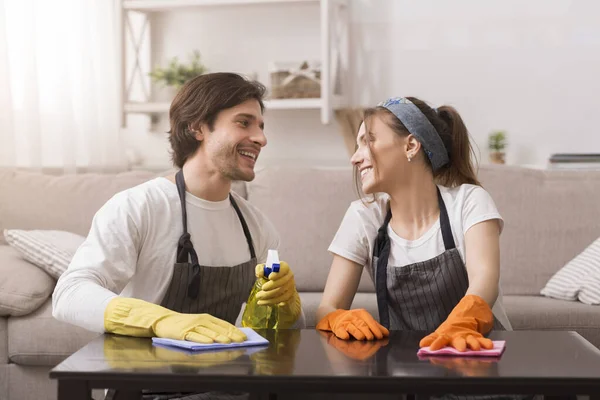 Casal jovem romântico amarrando juntos, limpando o pó da mesa — Fotografia de Stock