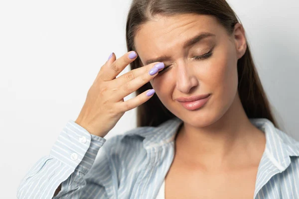 Menina tocando os olhos tendo conjuntivite em pé no fundo do estúdio branco — Fotografia de Stock