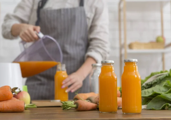 A nő narancsos turmixot önt egy turmixgépből egy pohárba. — Stock Fotó