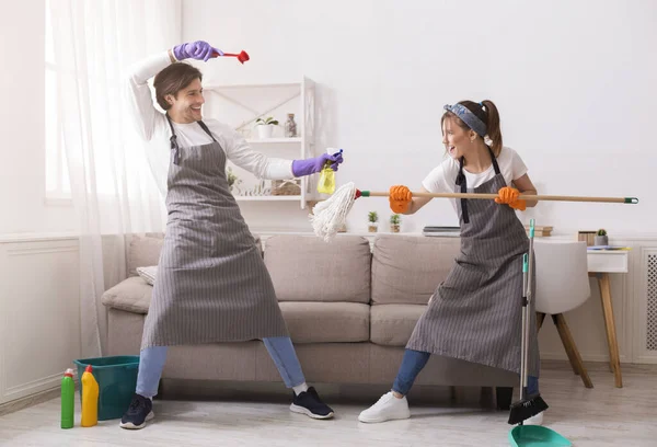 Casal feliz enganando ao limpar seu apartamento, lutando brincalhão — Fotografia de Stock