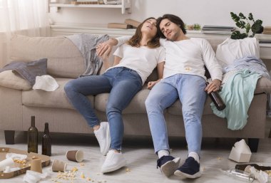 Partiden sonra. Dağınık odadaki kanepede uyuyan genç çift.