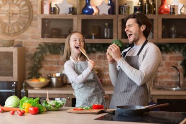 Baba ve kız mutfakta yemek hazırlarken eğleniyorlar, şarkı söylüyorlar.