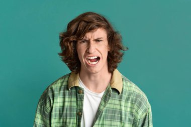 Öfkeni ifade et. Renkli arka planda öfkeli yüz ifadesi olan genç bir adam.