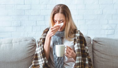 Bardaklı kız, covid-19 salgını sırasında burnunu siliyor.