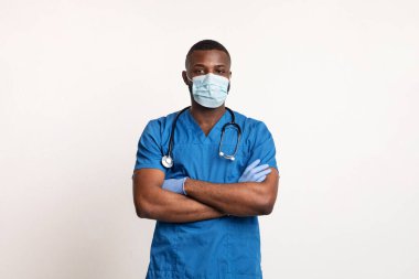 Yüzünde maske ve eldivenler olan kendine güvenen siyah doktor.