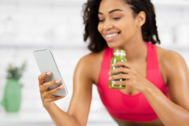 Gülümseyen kız Smoothie içiyor ve sosyal medyayı kontrol ediyor