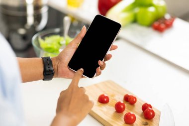 Siyah kız mutfakta boş ekranlı akıllı telefon kullanıyor.