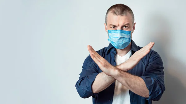 Людина в медичній масці Перетин рук стоїть над сірим тлом — стокове фото