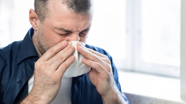 Volwassen man blazen neus in papier weefsel zittend thuis — Stockfoto