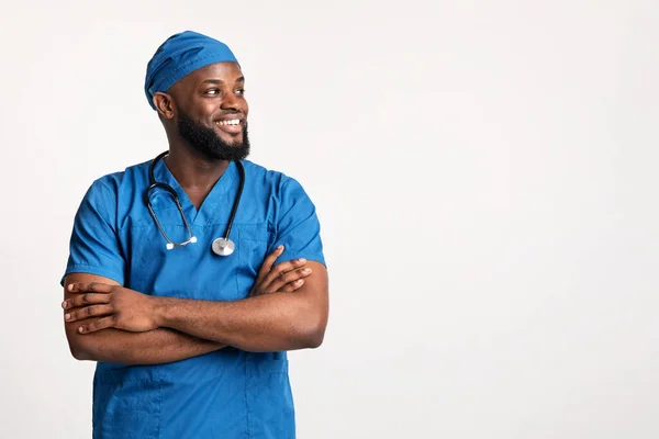 Jovem médico africano de uniforme azul olhando para o espaço vazio — Fotografia de Stock
