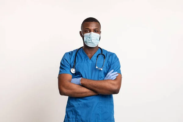 Selbstbewusster schwarzer Arzt mit Gesichtsmaske und Handschuhen über weißem — Stockfoto