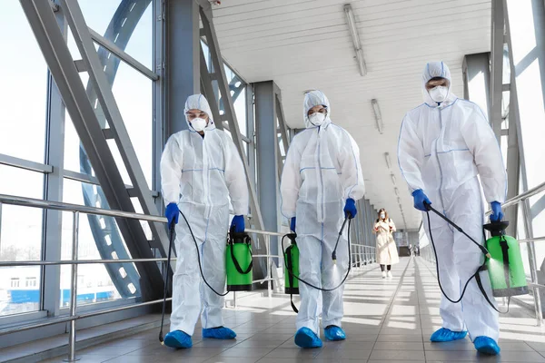 Arbeiter in Schutzanzügen tragen Fässer und desinfizieren alle Oberflächen — Stockfoto