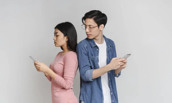 Asian man looking at his girlfriend phone while she chatting