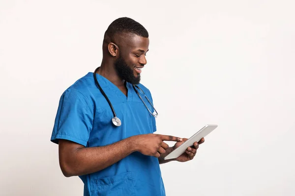 Junger schwarzer Chirurg mit digitalem Tablet über weißem — Stockfoto