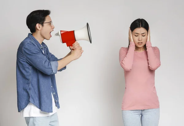 Naštvaný asijský chlap křičí megafonem na svou přítelkyni — Stock fotografie