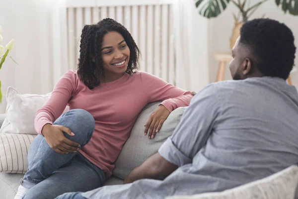 Married black couple chatting and resting on couch at home